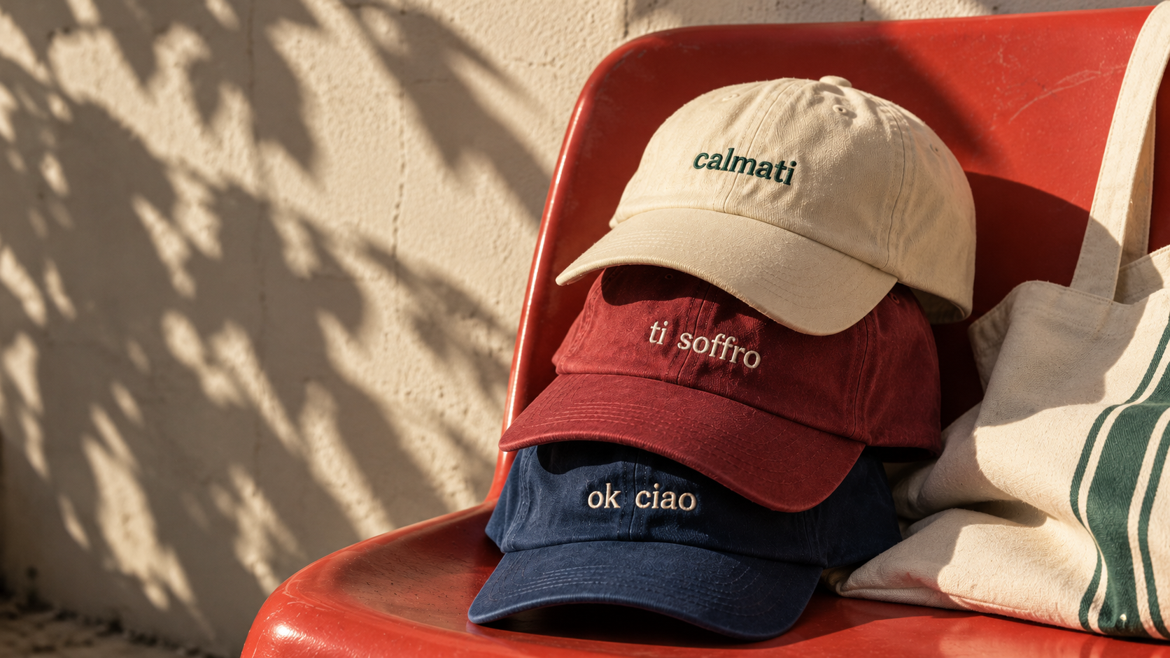 Cappellini Fuori Contesto impilati su una sedia rossa accanto a una borsa in tela